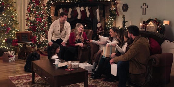 a little women's christmas opening presents on couch