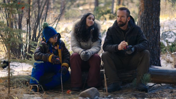 ben, sam and jason sitting on log in wilderness