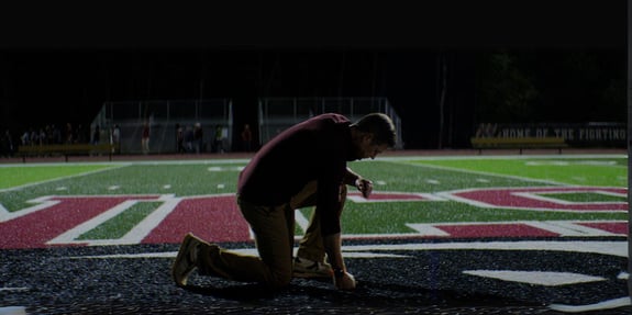 average joe joe kennedy knealing in prayer at 50 yard line